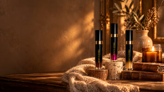 Les trois huiles à lèvres Secrets d'Autrefois, Marron Glacé, Rose et Nacrée, dans un décor cocooning à la lueur d'une bougie